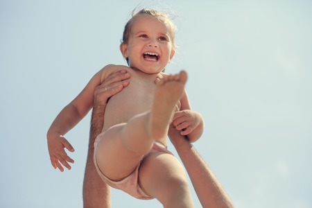 Happy baby in father's hands. Toned image. Shallow depth of field. Selective focus.の写真素材