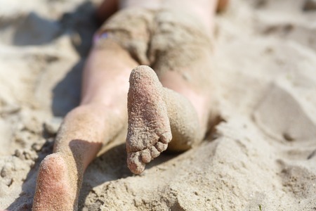 Child's feet in the sand on the beach. Shallow depth of field. Selective focus.の写真素材