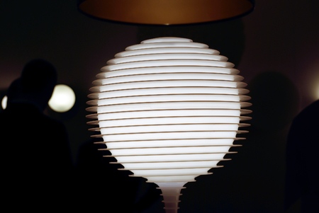 Abstract image of glowing glass lamp with stripes on dark background.