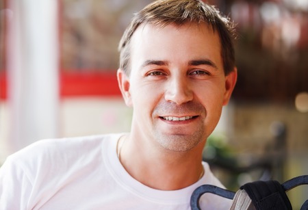 Close-up portrait of a smiling young man. Male looks into the camera. Selective focus on the model's face.の写真素材