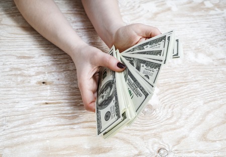 Cash in hands. Pile of one hundred dollar bills. Stack of dollars in hands. Woman counting money. Dollars in hands. Fake money in hands.の写真素材