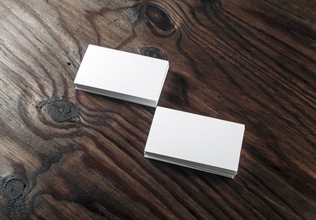 Blank white business cards on dark wooden background. Mock-up for branding identity. Blank template for design presentations and portfolios.の写真素材