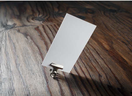 Blank business card in the paper clip on wooden background. For design presentations and portfolios. Mock-up for branding identity. Shallow depth of field. Selective focus.の写真素材