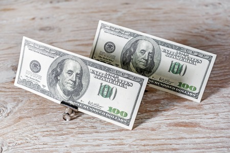 Money in the paper clips.One hundred dollar bills in paper clips standing on a dark wooden background. Fake money.の写真素材