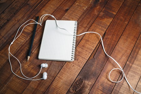 Photo of blank diary with a pencil and headphones on vintage wooden table background. Mock-up for design presentations and portfolios. Diary, pencil and headphones. Top view.の写真素材