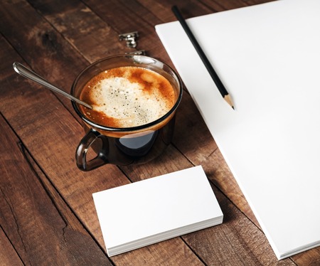 Blank paperwork template on vintage wooden background. Close-up of blank stationery paper, letterhead, coffee cup and pencil. Mock-up for design portfolios.の写真素材