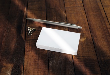 Blank business cards, pen and paper clip on vintage wooden table background.の写真素材