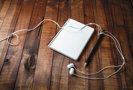 Blank sketchbook with a pencil and headphones on vintage wooden table background. Template for graphic designers portfolios.の写真素材