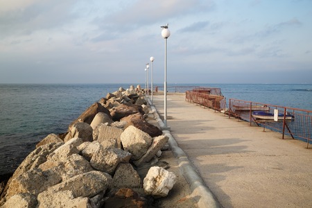 Breakwater extending in the sea. Pierce with lampposts. Calm summer day on the coast of the Black Sea.の写真素材