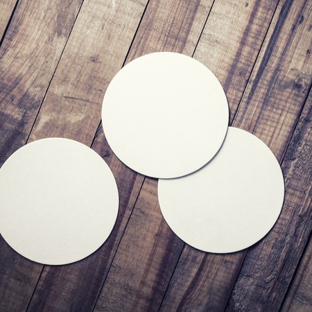 Three blank beer coasters on vintage wooden table background. Responsive design mockup. Top view.の写真素材