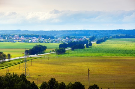 Bright summer countryside landscape. Meadows, fields, trees, road and houses in the countryside. Minsk region, Belarusの写真素材