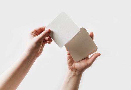 Blank square beer coasters in female hands.の写真素材