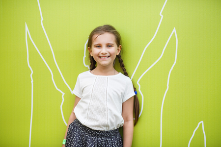 Smiling little girl child on light green background. Concept of happy family.の写真素材