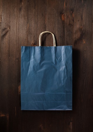Blank blue paper shopping bag on wooden background. Flat lay.の写真素材