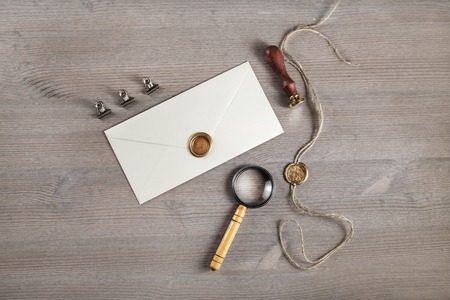Vintage letter envelope with golden wax seal, stamp and magnifier, at wood table background. Mock-up...