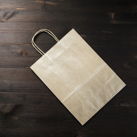 Blank craft paper bag on wood table background. Flat lay.の写真素材
