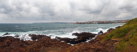Waves crashing on rough shores. Sea waves crash and splash on rocks. Panoramic shot.の写真素材