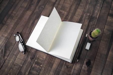 Opened blank book, stationery on wooden background. Notebook, glasses, pencil, eraser and cactus