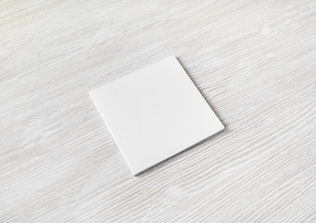Blank square brochure on light wooden background. Responsive design template.