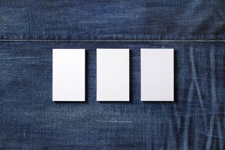 Three blank business cards on denim background. Branding mockup. Flat lay.