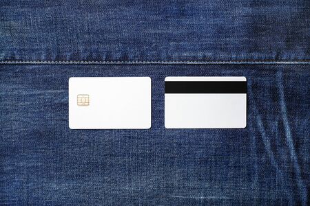 Two blank white plastic credit cards on denim background. Chip cards. Front and back view. Flat lay.の写真素材