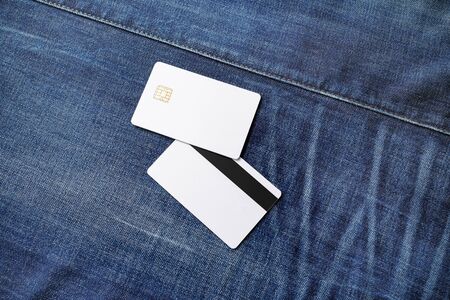 Credit cards mockup. Two blank white plastic chip cards on denim background. Front and back view.