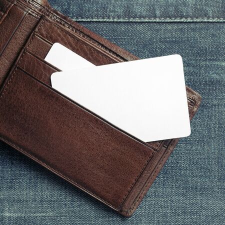 Blank business card or discount card in leather wallet on denim background. Copy space for text....