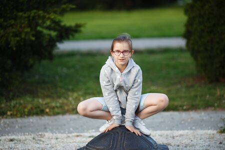 Girl child posing in a frog pose in the park. Child on the playground. Selective focus.の写真素材