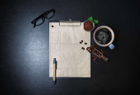 Blank vintage stationery set and coffee on black table background. Clipboard with blank kraft...
