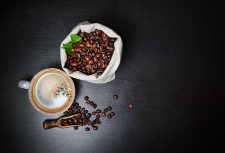 Coffee cup and coffee beans on black wood table background. Copy space for your text. Flat lay.の写真素材