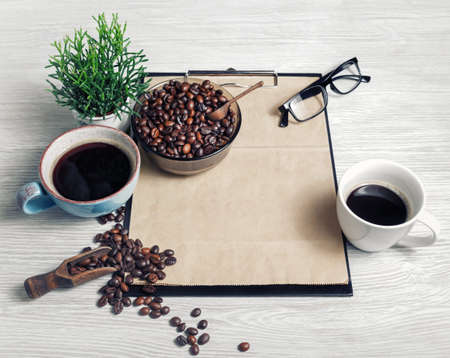 Still life with coffee and clipboard on light wood table background.