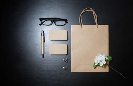 Photo of blank kraft paper stationery set and flowers on black table background. Top view. Flat lay.の写真素材