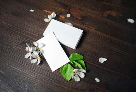 Blank white business cards and flowers on wood table background. Mockup for ID. Template for graphic...