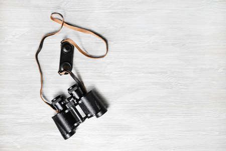 Photo of vintage black binoculars on light wood table background. Copy space for your text. Flat lay.の写真素材
