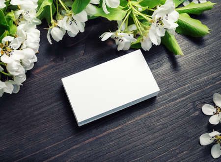Photo of blank business cards with spring flowers on wooden background. Mockup for branding ID.の写真素材