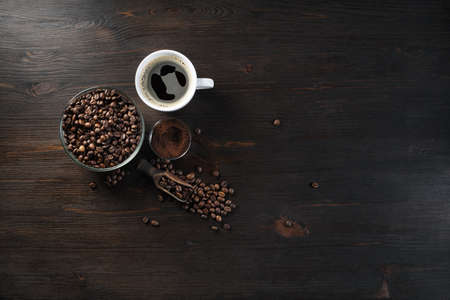 Vintage coffee background. Coffee cup, roasted coffee beans and ground powder on wood kitchen...