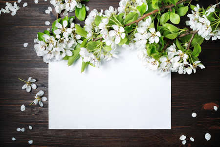 Photo of blank paper poster and spring flowers on wooden background. Responsive design mockup. Flat lay.の写真素材