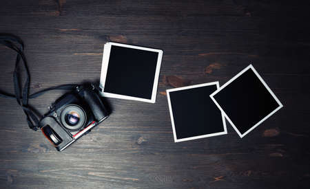Vintage camera and blank square photo frames on vintage wooden background. For design presentations and portfolios. Flat lay.の写真素材