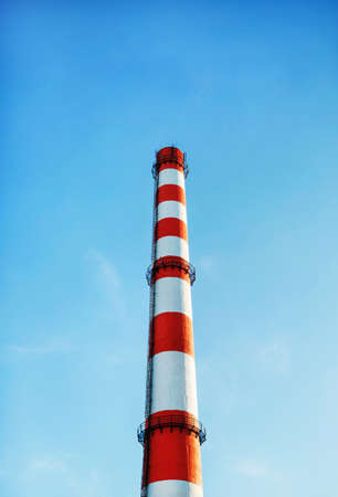 Factory chimney against blue sky background. Vertical shot.の写真素材