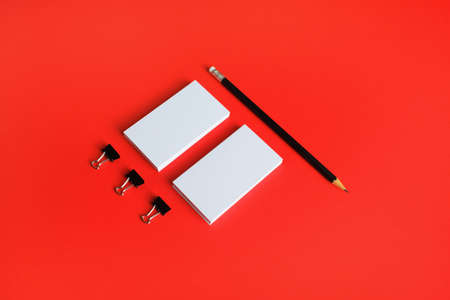 Blank business cards and pencil on red paper background. Stationery mock up. Template for placing your design.の写真素材