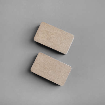 Photo of blank kraft paper business cards on gray paper background. Template for ID. Flat lay.
