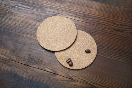 Blank cork beer coasters and coffee beans on wooden background. Responsive design template.の写真素材