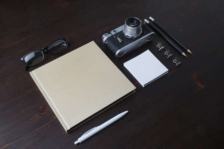 Blank vintage stationery and retro photo camera on wooden background.