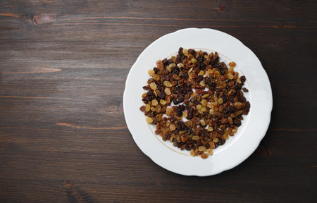 Raisins in plate on wood table background. Flat lay.の写真素材