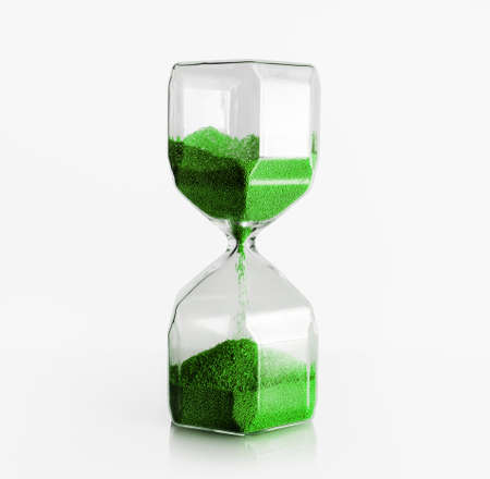 Hourglass with green filler on light background. Time concept.の写真素材