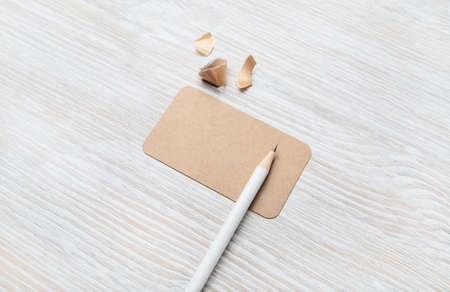 Blank kraft business card and pencil on light wood table background. Template for graphic designers...