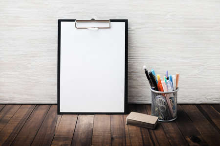 Photo of stationery set. Clipboard with blank letterhead, cup holder with pencils and pens, business...