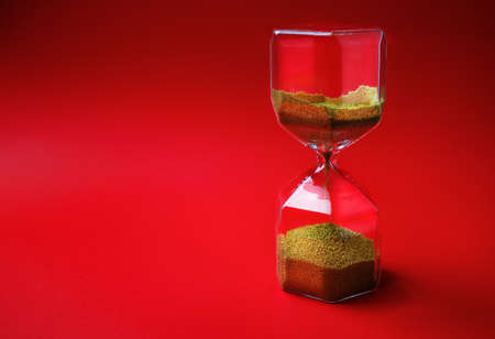 Hourglass on red background with copy space. Time concept.の写真素材