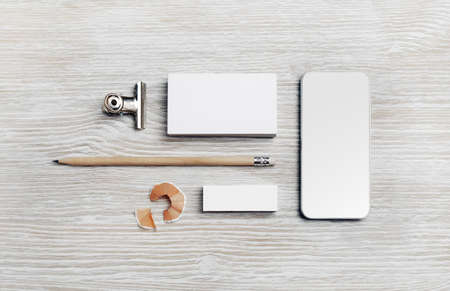 Branding mock up. Blank business card, smartphone, pencil and eraser on light wooden background. Flat lay.の写真素材