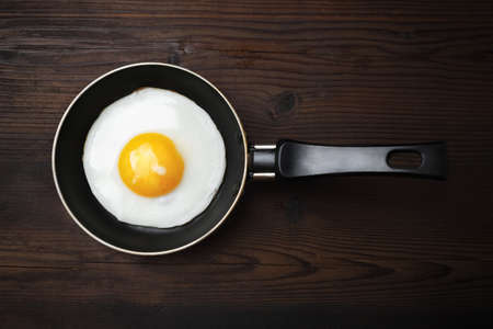 Fried egg in frying pan on wooden background. Flat lay.の写真素材